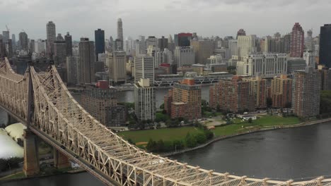 rising drone aerial shot looking across roosevelt island next to the queensboro bridge at the east river towards manhattan, nyc in the daytime