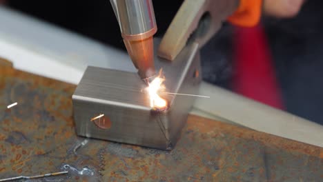 Laser-welding-machine-with-hand-hold-gun.-Laser-welding-is-shown-in-close-up.