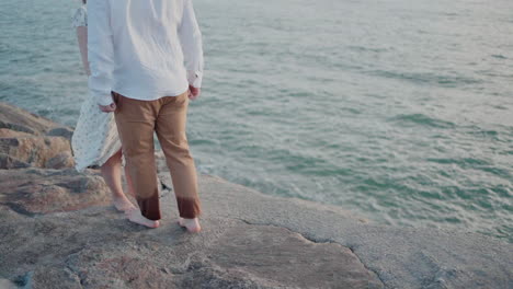 Couple-holding-hands-on-rocky-shore-at-Ovar,-Portugal