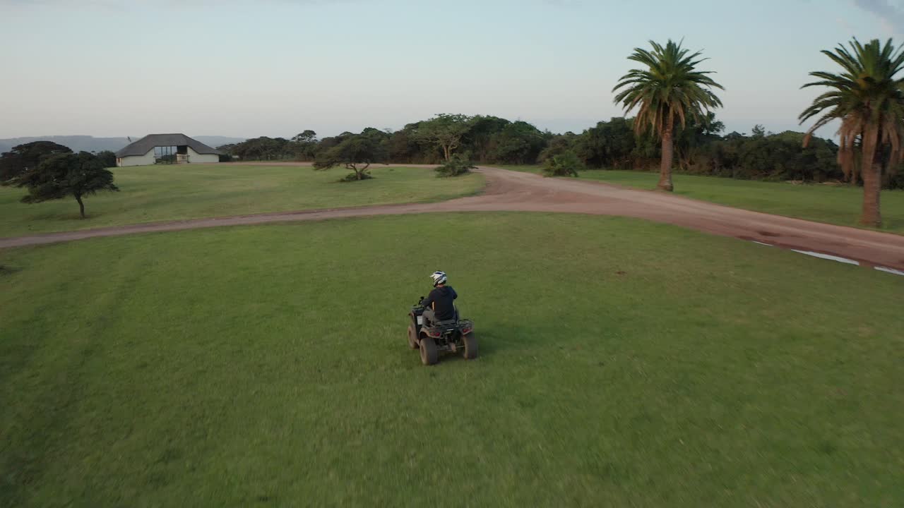 Person riding an ATV through a large grassy field