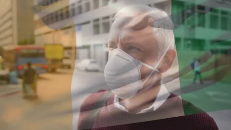 Animation-of-flag-of-ivory-coast-waving-over-man-wearing-face-mask-during-covid-19-pandemic