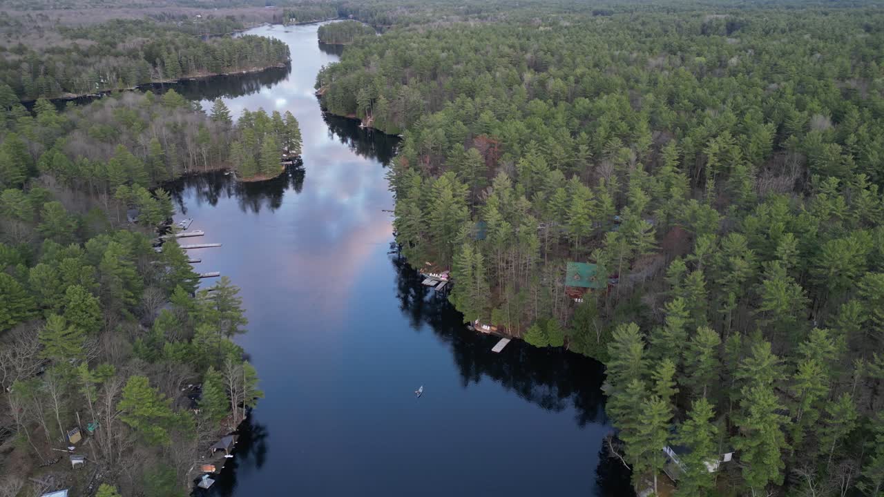 vista aérea de una persona en canoa en un río tranquilo que serpentea a través de un denso bosque, rodeado de exuberante vegetación y belleza natural