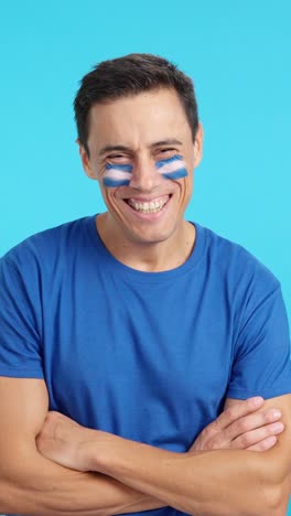 man standing with salvadoran flag painted on face smiling