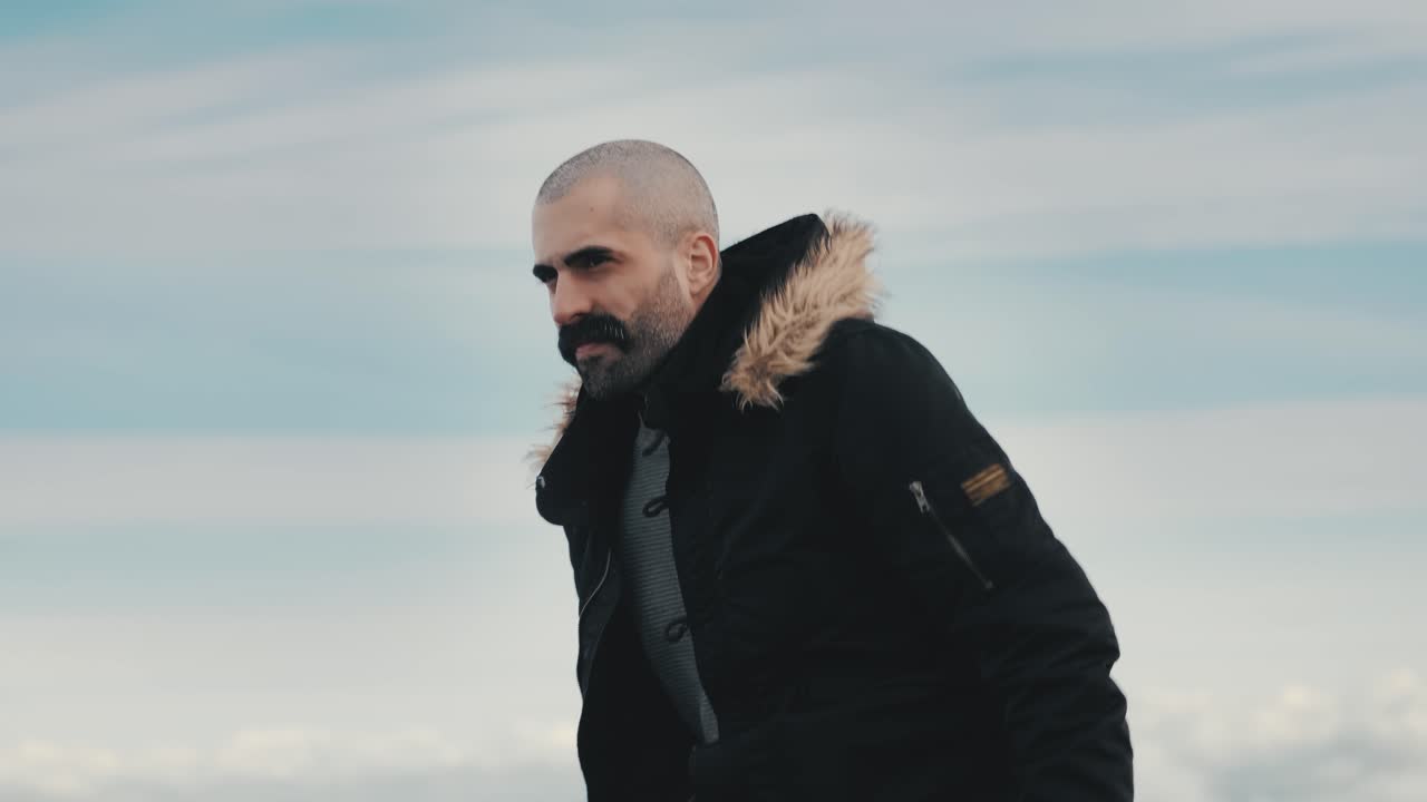 hombre guapo escalando una roca, disfrutando de las impresionantes vistas de las montañas y las nubes en el horizonte