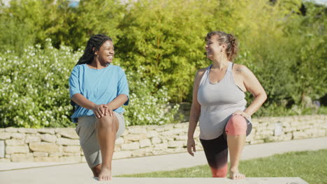 front view of happy fat women stretching legs together outside