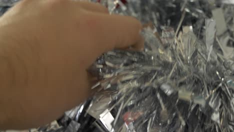 picking up silver christmas tinsel from a decoration box