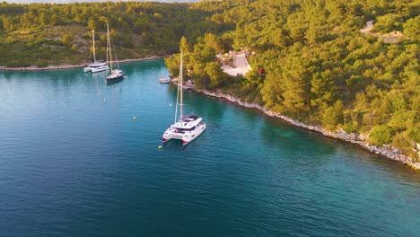 Flug-über-Die-Bucht,-In-Der-Yachten-Umgeben-Von-Grünen-Bäumen-Vor-Der-Kulisse-Von-Bergen-Und-Einer-Bergstraße-Treiben