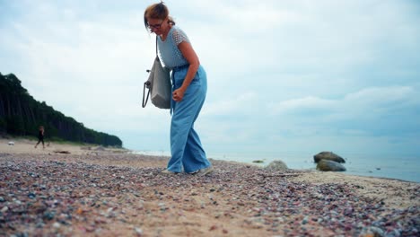 Mujer-Con-Una-Bolsa-Recogiendo-Algunas-Piedras-En-La-Playa-De-Karkle-En-Lituania