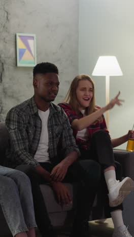 nervous african-american man throws ball into tv while watches failure match with friends at home slow motion. offended sports fan and companions at game