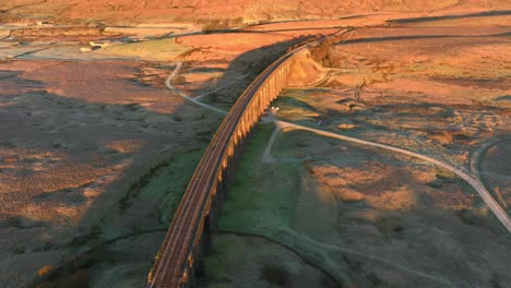 puente ferroviario con muchos arcos que atraviesa el páramo desolado al amanecer en invierno