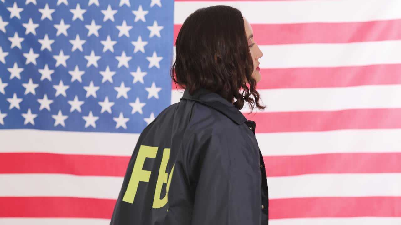 Agente donna mostra la giacca dell'FBI davanti alla bandiera americana