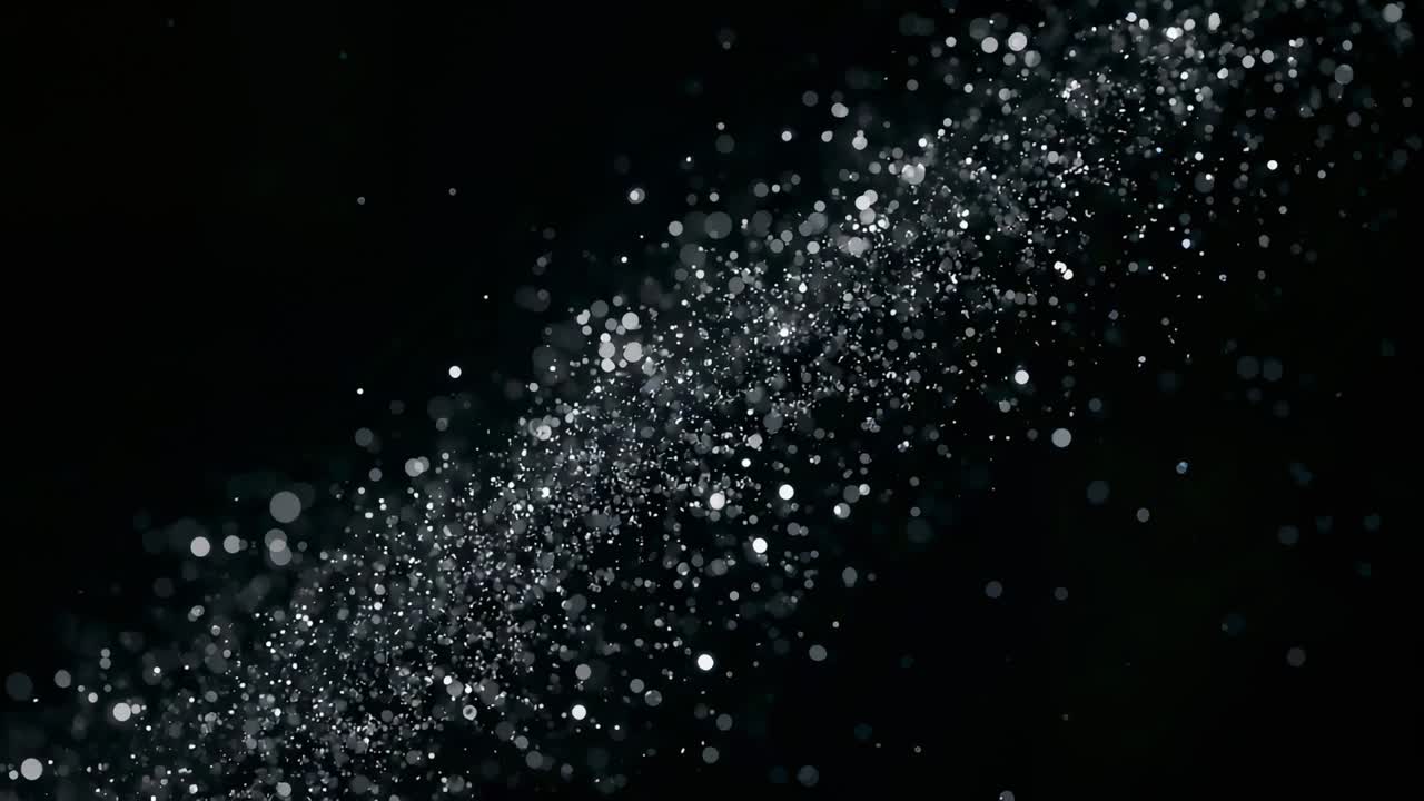 Mustalla taustalla kääntyilevä, ohut glitterinauha, jonka tarkennus muuttuu ja luo bokeh-ympyröitä