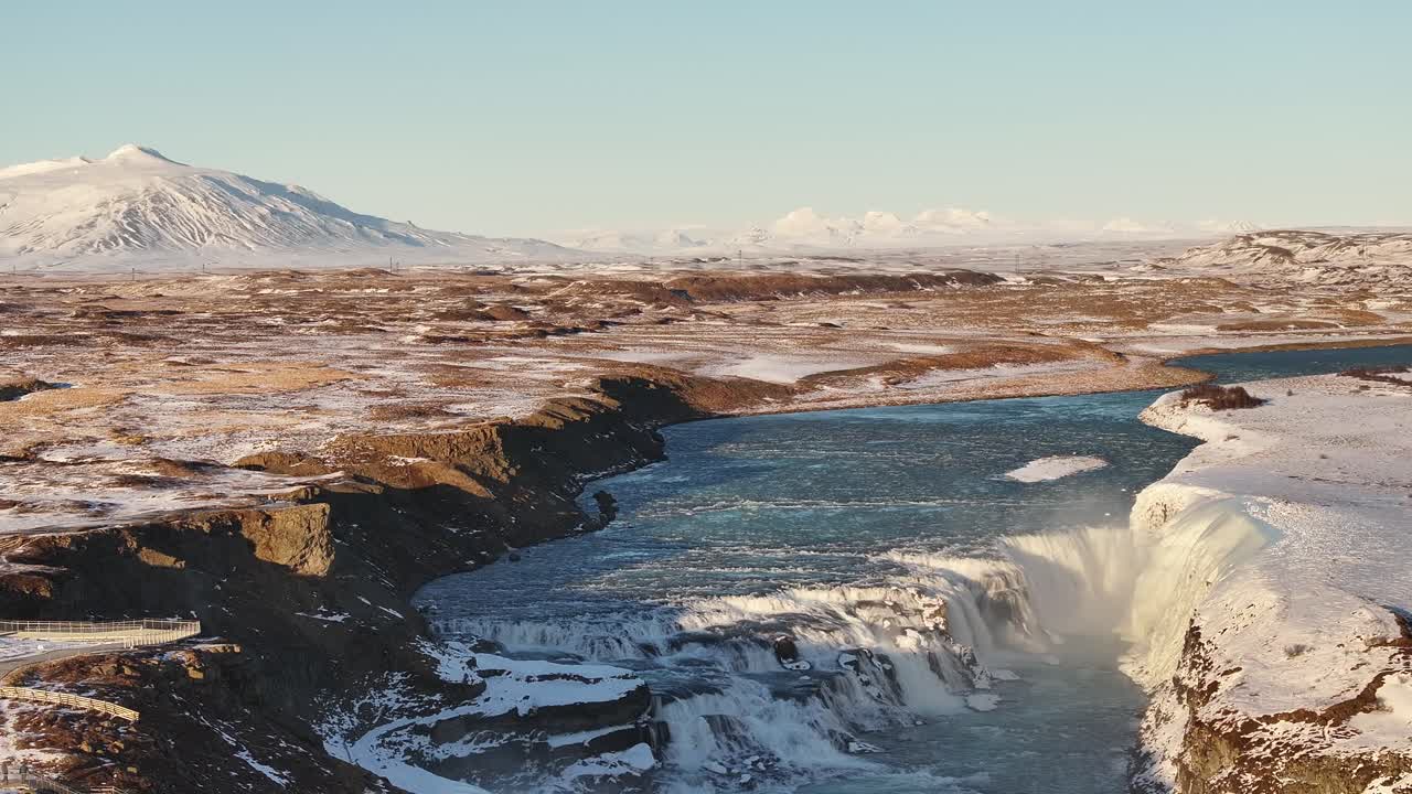 Majestic Gullfoss waterfall cascading down icy cliffs in the winter landscape of Suðurland, Iceland, with the Hvítá River flowing through the rugged terrain.