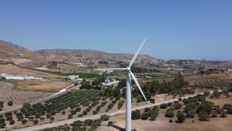 aerial view: wind turbine turning in wind on mediterranean hillside