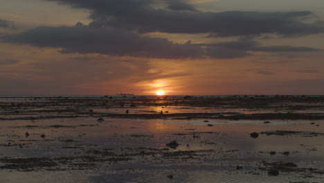 Blick-Auf-Den-Sonnenuntergang-Bei-Ebbe-Mit-Einem-Frachtboot-Aus-Der-Ferne-4k