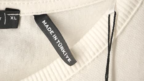 close-up of clothing tags on a cream-colored sweater