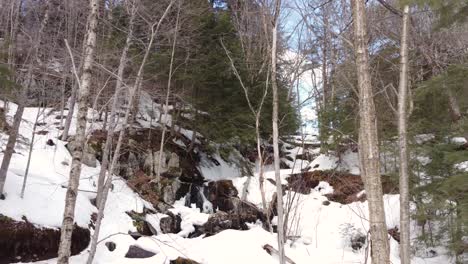 Aerial-dolly-approaches-stunning-snow-winter-wonderland-and-frozen-waterfall-among-aspen-trees