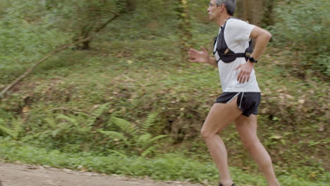 male sportsman in shorts and t-shirt running on trail in forest