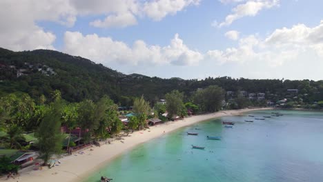 4k aerial drone footage orbit shot of salad beach on koh phangan in thailand with fishing boats, teal water, coral, and green jungles