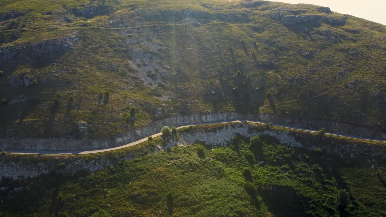 pan aérea de un estrecho camino de montaña debajo de los picos al amanecer