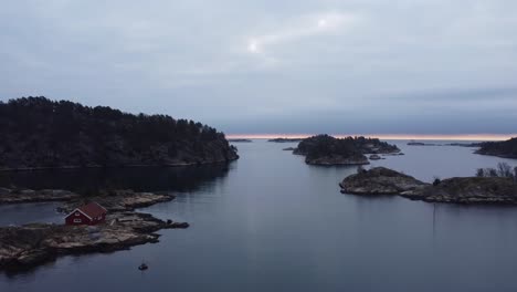 Abendantenne---Flug-über-Der-Meeresoberfläche-In-Lillesand,-Norwegen-In-Richtung-Horizont-Und-Nordsee---Bewölkter-Himmel-Und-Dunkle-Küsteninseln-Risholmen,-Hoyholmen-Und-Tjuvholmen