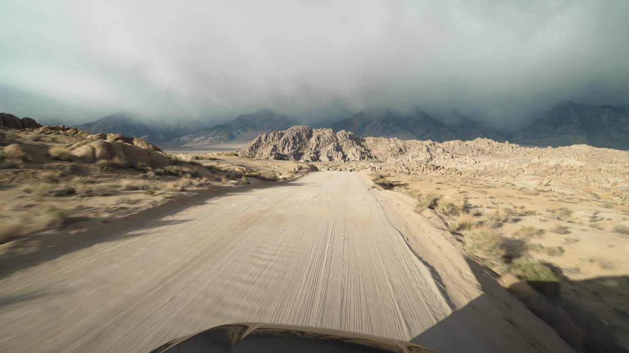 View from a moving car that is driving in desert with mountains in Alabama Hills on American road trip