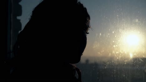 woman silhouette with eyelashes near window at sunset light