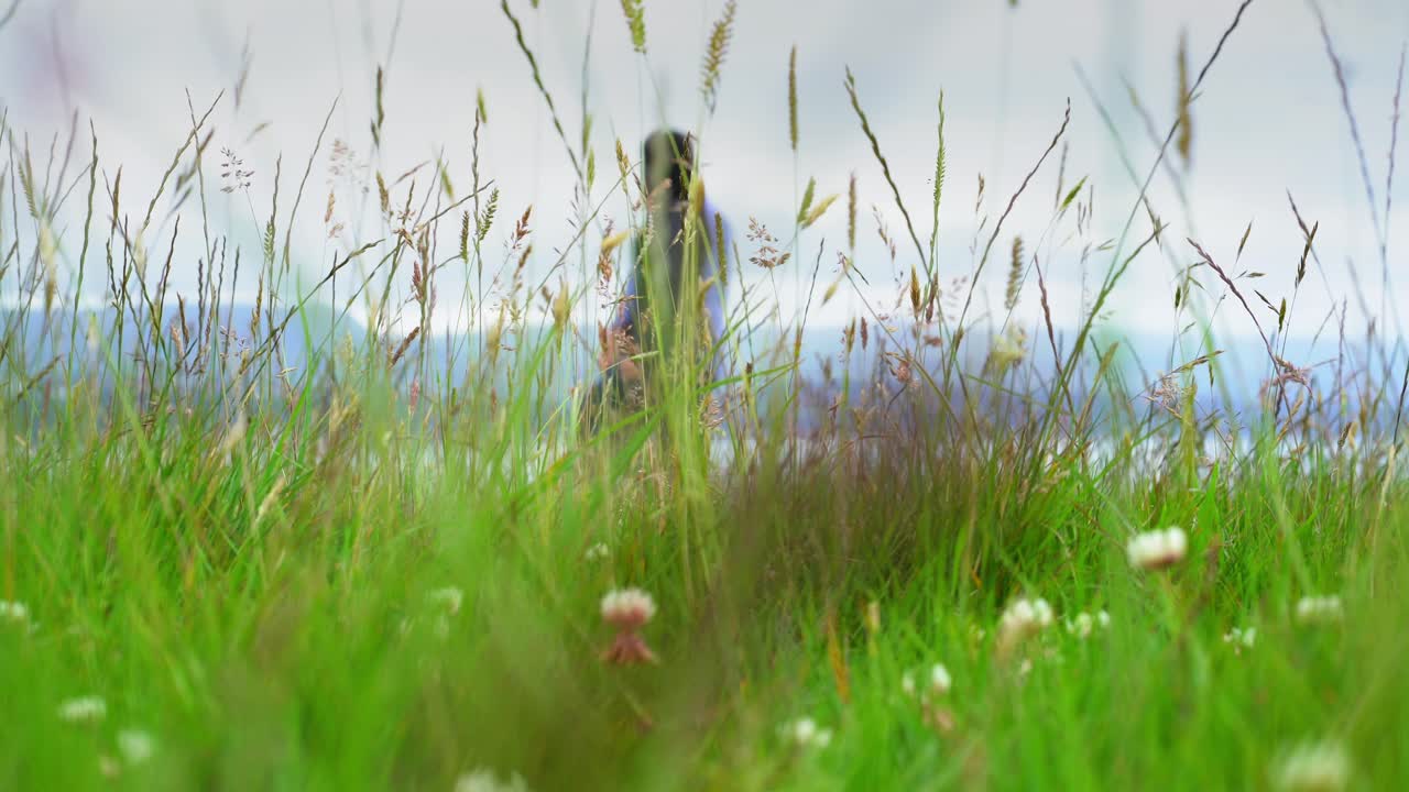 Couple on romantic walk in green field beside the sea long grass blurry