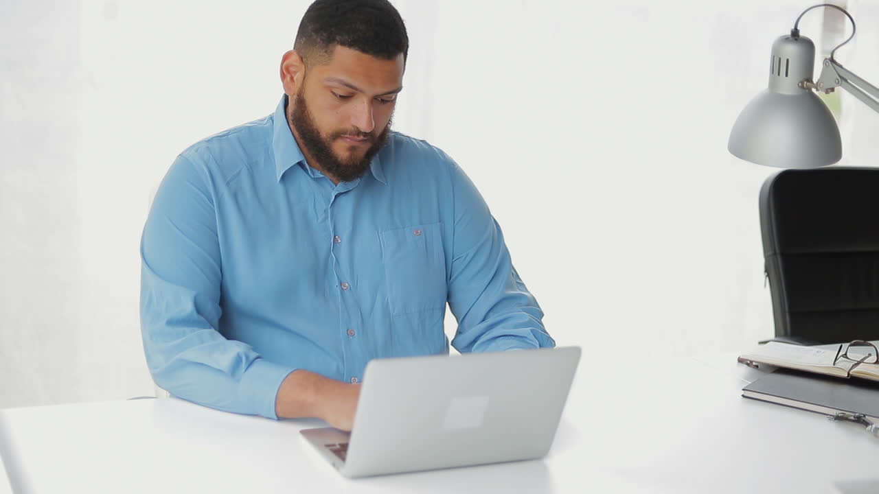 un joven concentrado escribiendo en una computadora portátil.