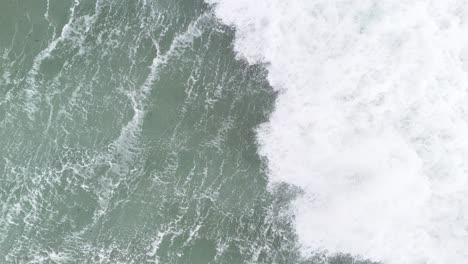 onda en cámara lenta estrellándose en el mar sobre las aves ojo dron vista aérea 4k