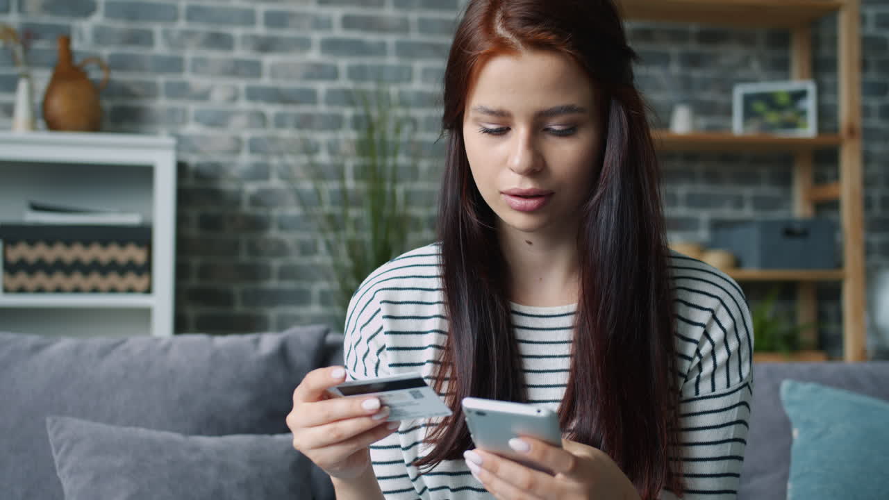 Donna che effettua un pagamento online con carta di credito e smartphone a casa