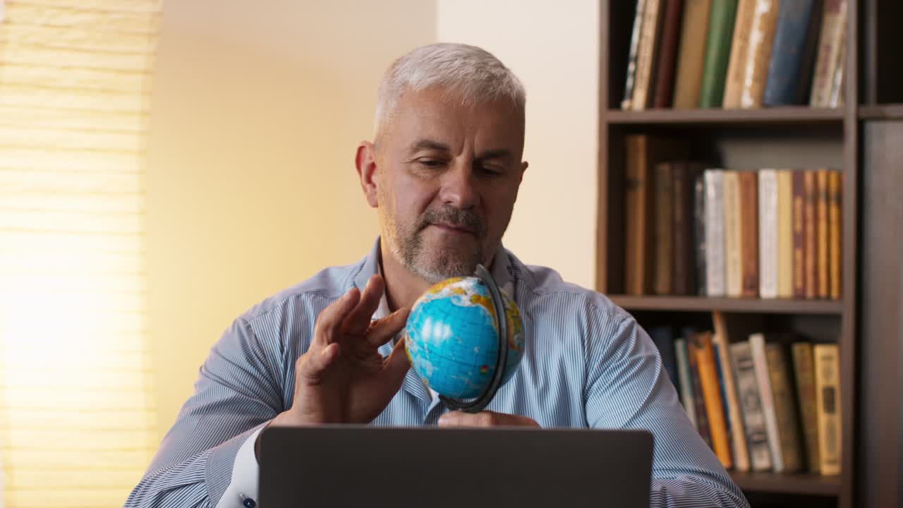 hombre estudiando un globo en una computadora portátil en casa