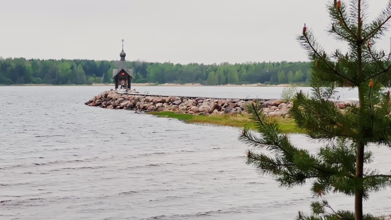 오래된 예배당은 레닌그라드 지방의 물 위에 있는 돌로 된 산꼭대기에 서 있습니다. 러시아의 구름이 많은 날씨에 숲이 배경입니다.