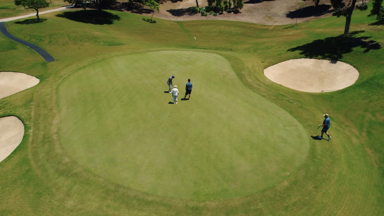 Ripresa aerea ravvicinata di golfisti che imbucano durante una partita di golf presso il campo da golf El Paraiso a Marbella, Spagna.