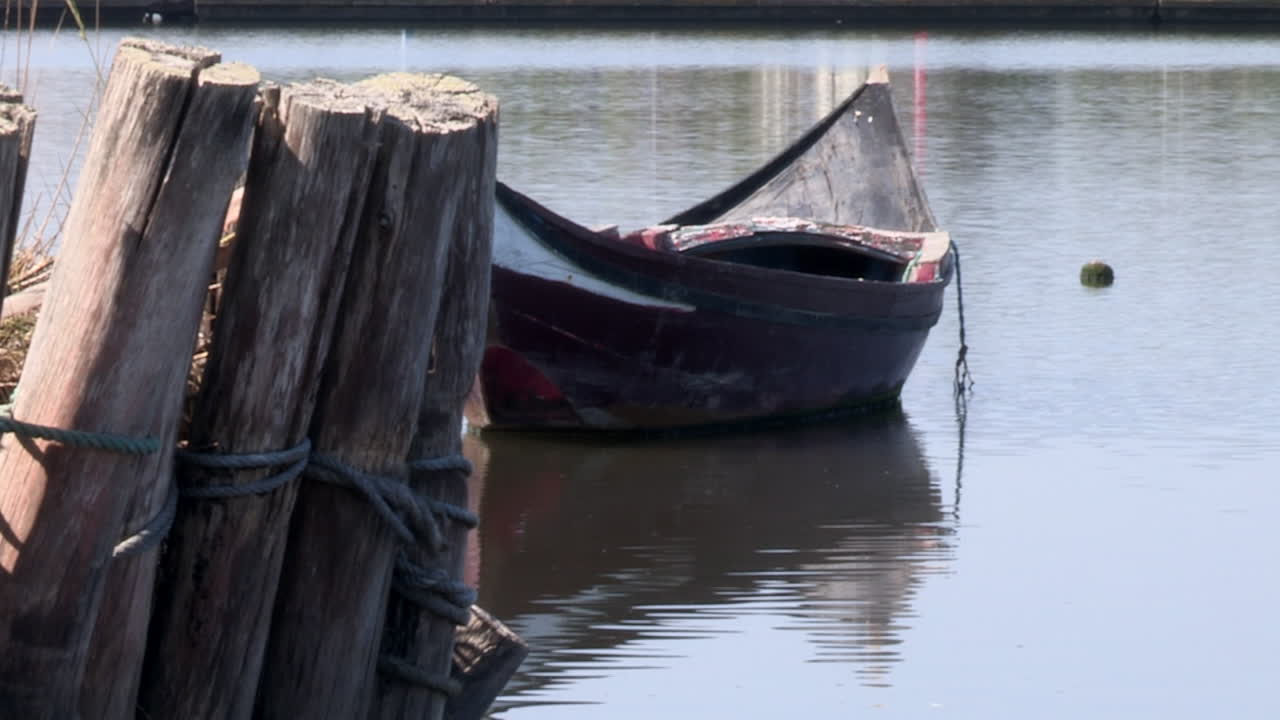 pequeño barco de madera amarrado en el río, troncos erguidos para sostener las orillas del río