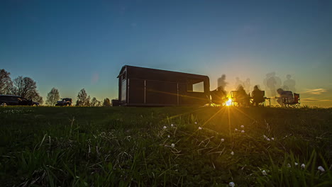 Silhouette-of-people-enjoying-the-sunrise-and-breakfast-at-a-camping-trailer---time-lapse