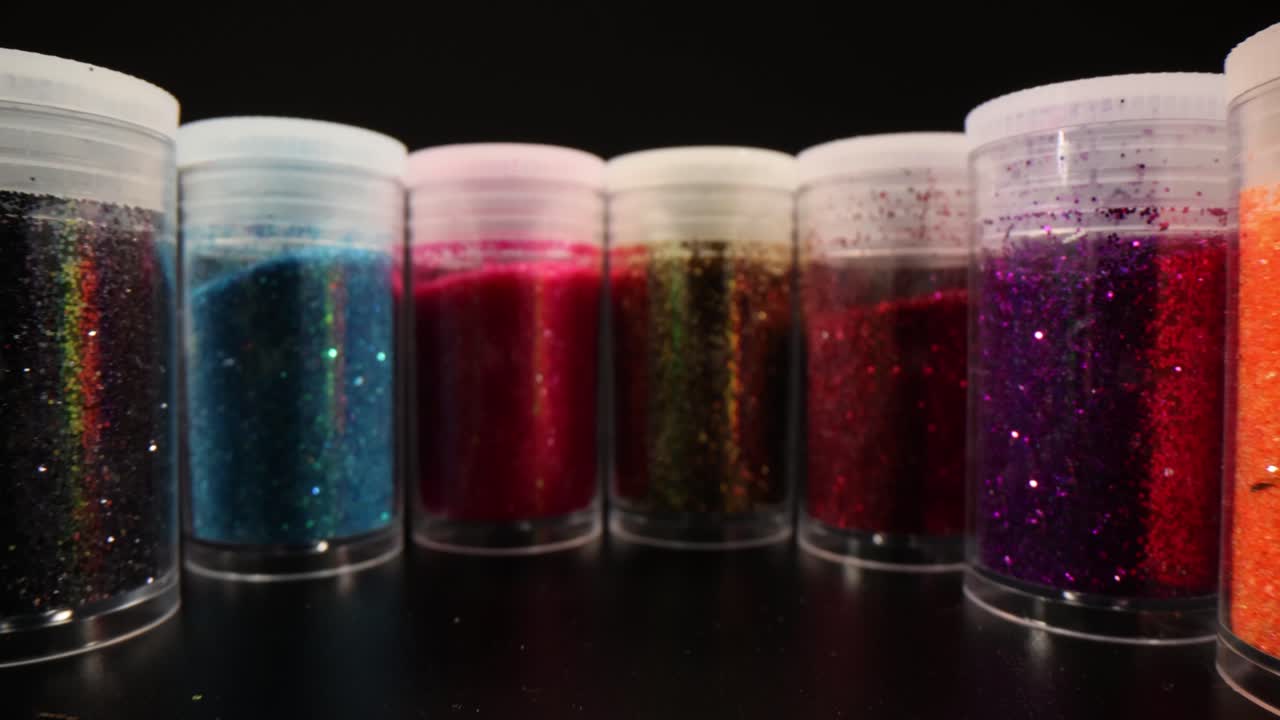 Close-up of Colorful Glitter Jars on Black Background