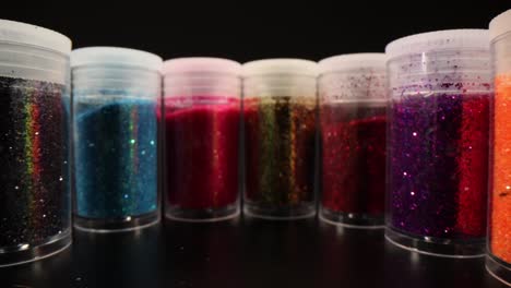 close-up of colorful glitter jars on black background