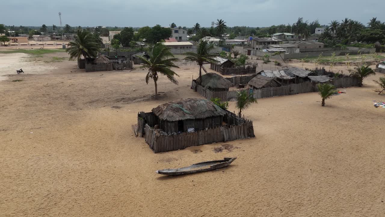 Cena cinematográfica de drone da costa tropical em Lomé, Togo. Com ondas quebrando, uma extensa faixa de areia e o vasto horizonte atlântico sob um céu nublado.