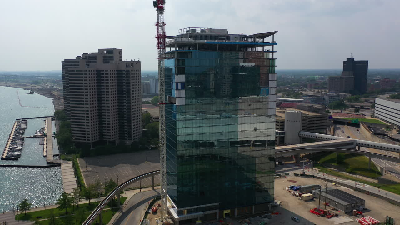 drone disparado elevándose hacia un rascacielos a la orilla del río en construcción, en los estados unidos soleados