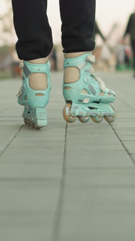 un primer plano de patines en movimiento, deslizándose a través de un camino pavimentado del parque. el fondo está borroso, con personas y bancos, capturando el movimiento dinámico y el entorno del parque urbano