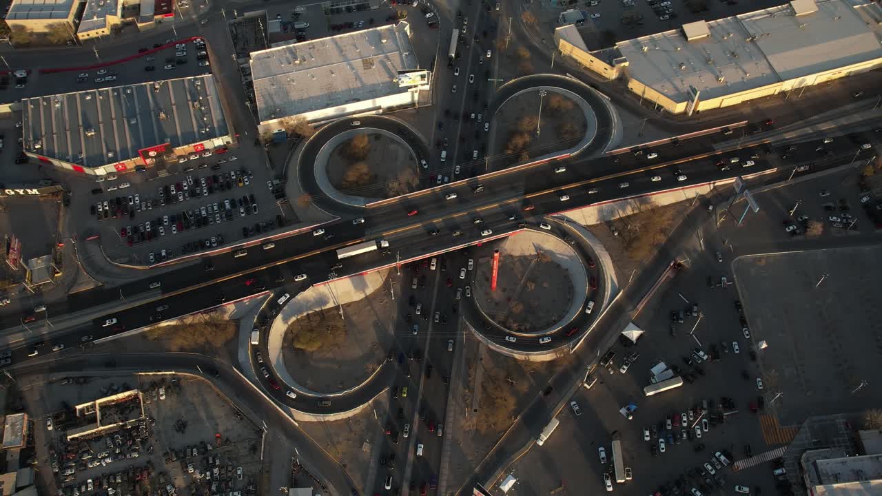 Slow motion zenithal shot of busy traffic on a cloverleaf interchange with cars moving through the lanes.