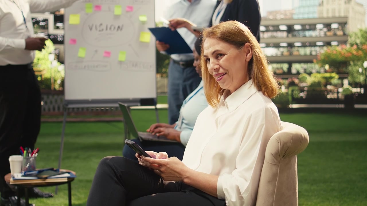 Professional Woman Using Smartphone During Outdoor Office Meeting