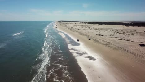 Vista-Aérea-De-Drones-De-La-Conducción-De-Vehículos-En-La-Playa-Durante-La-Marea-Baja-En-Una-Isla-Barrera-De-La-Costa-Del-Golfo-En-Una-Tarde-Soleada---Isla-Del-Padre-Sur,-Texas