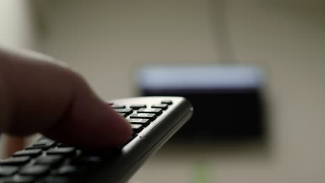 primer plano de la mano del hombre con el control remoto y viendo la televisión con prensas para cambiar el canal en el botón