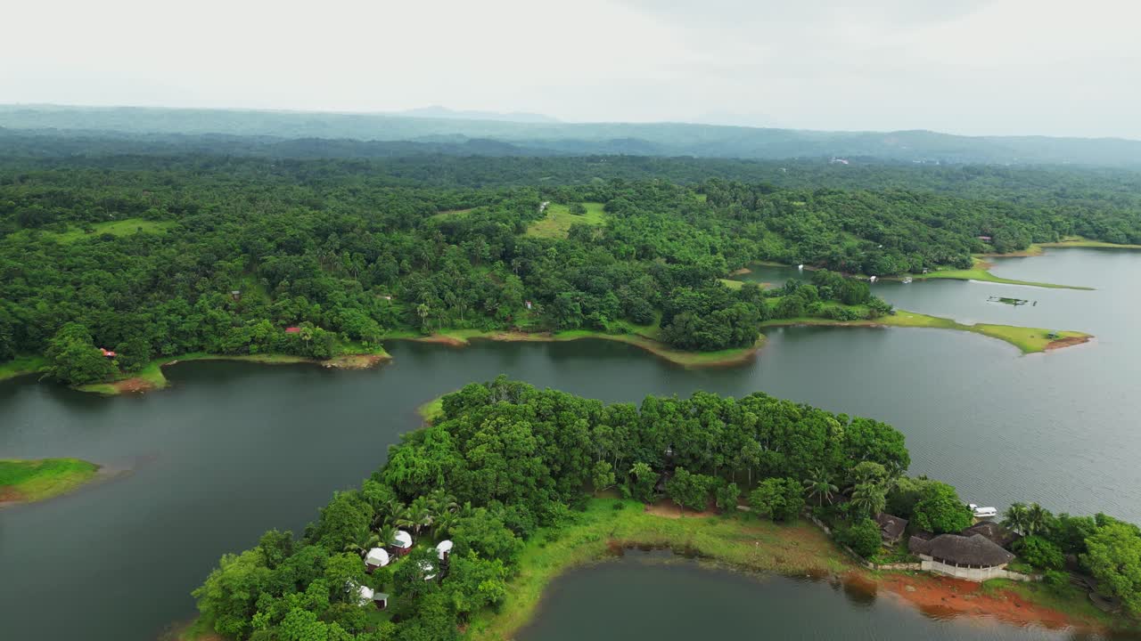 A drone starts semi-top view, tilts down to level with lake and green trees—creating a cinematic reveal of calm waters and lush surroundings in Laguna
