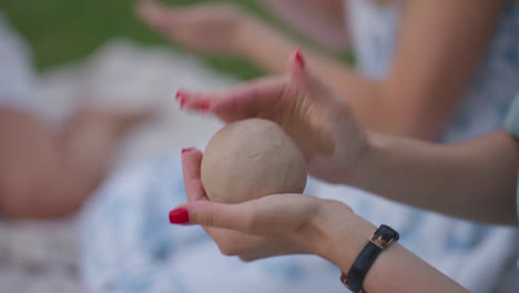 Women's-hands-close-up-sculpt-an-object-from-clay-in-a-group-of-people-in-nature-in-an-open-area.-Master-class-in-clay-modeling-hobby-handmade.-Modeling-of-the-product-in-close-up.