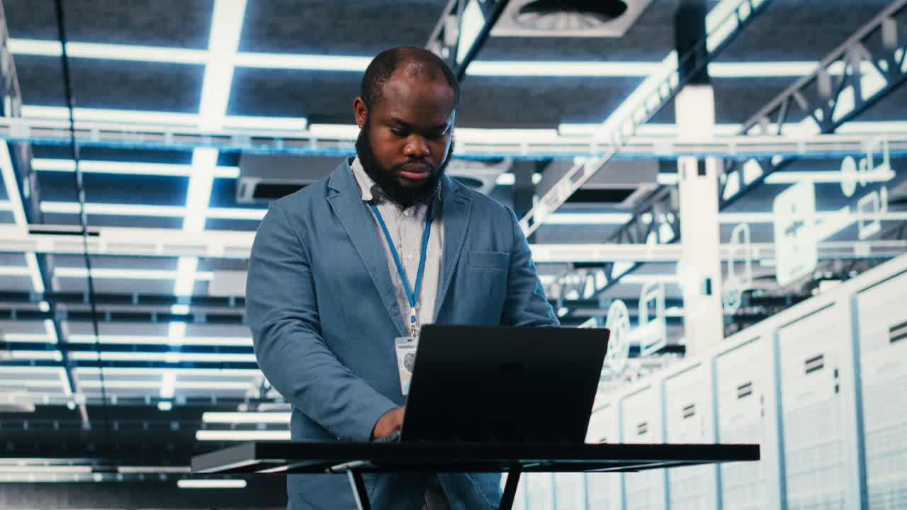 African American Man Typing on Laptop in Data Center