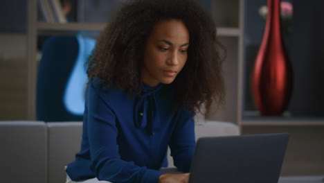 Focused-african-american-businesswoman-typing-laptop-answering-call-in-office.