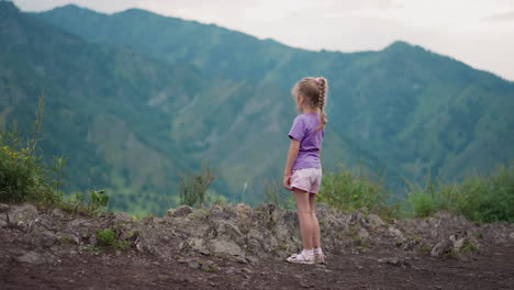 una niña pensativa mira las siluetas de las viejas montañas